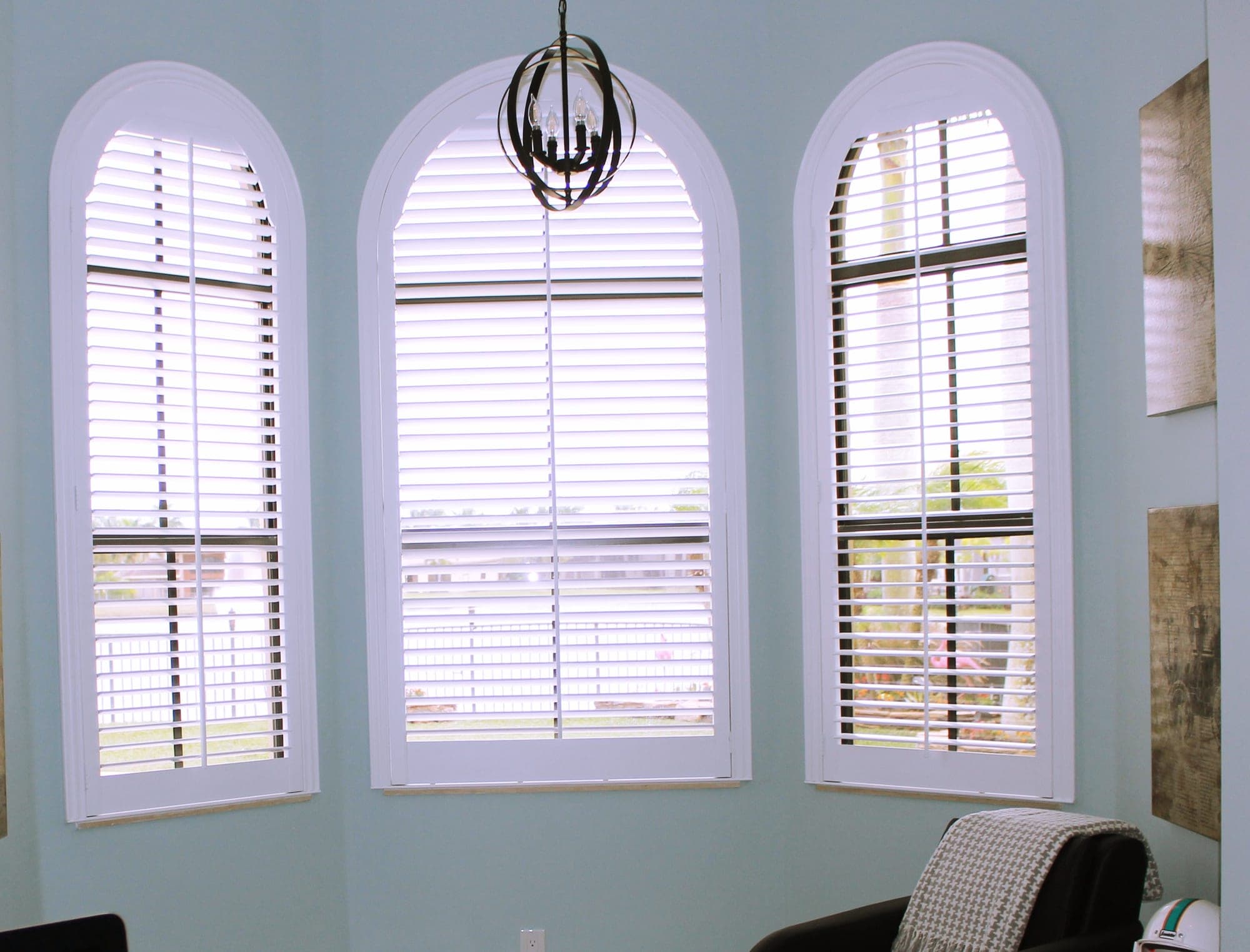 Arched windows fitted with white louvered plantation shutters